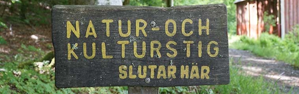 En träskylt med texten "Natur- och kulturstig slutar här" i ett naturområde