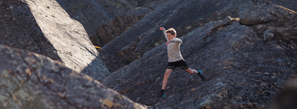 Ung person hoppar på klippor.
