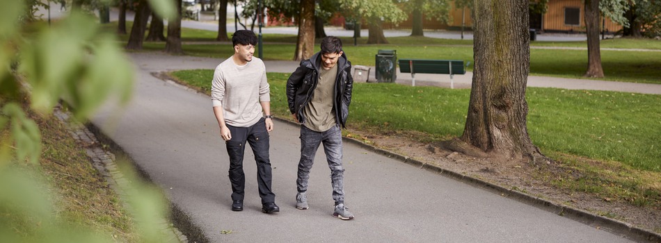 Två killar promenerar i en park.
