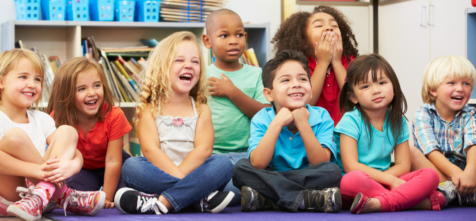 Flera glada barn sittandes på en matta i ett klassrum