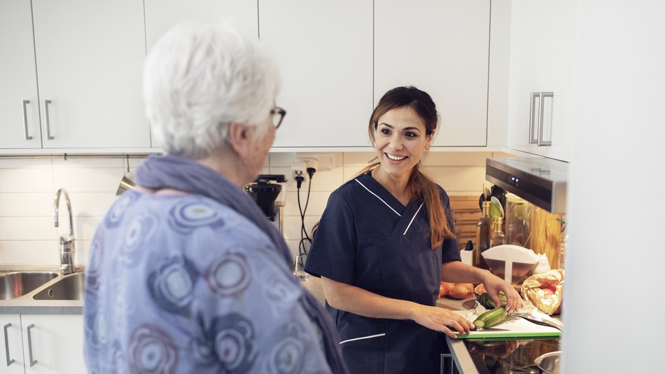 Hemtjänstpersonal hjälper äldre person med matlagning.