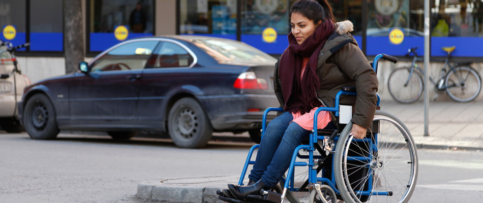 kvinna i rullstol på väg över övergångsställe